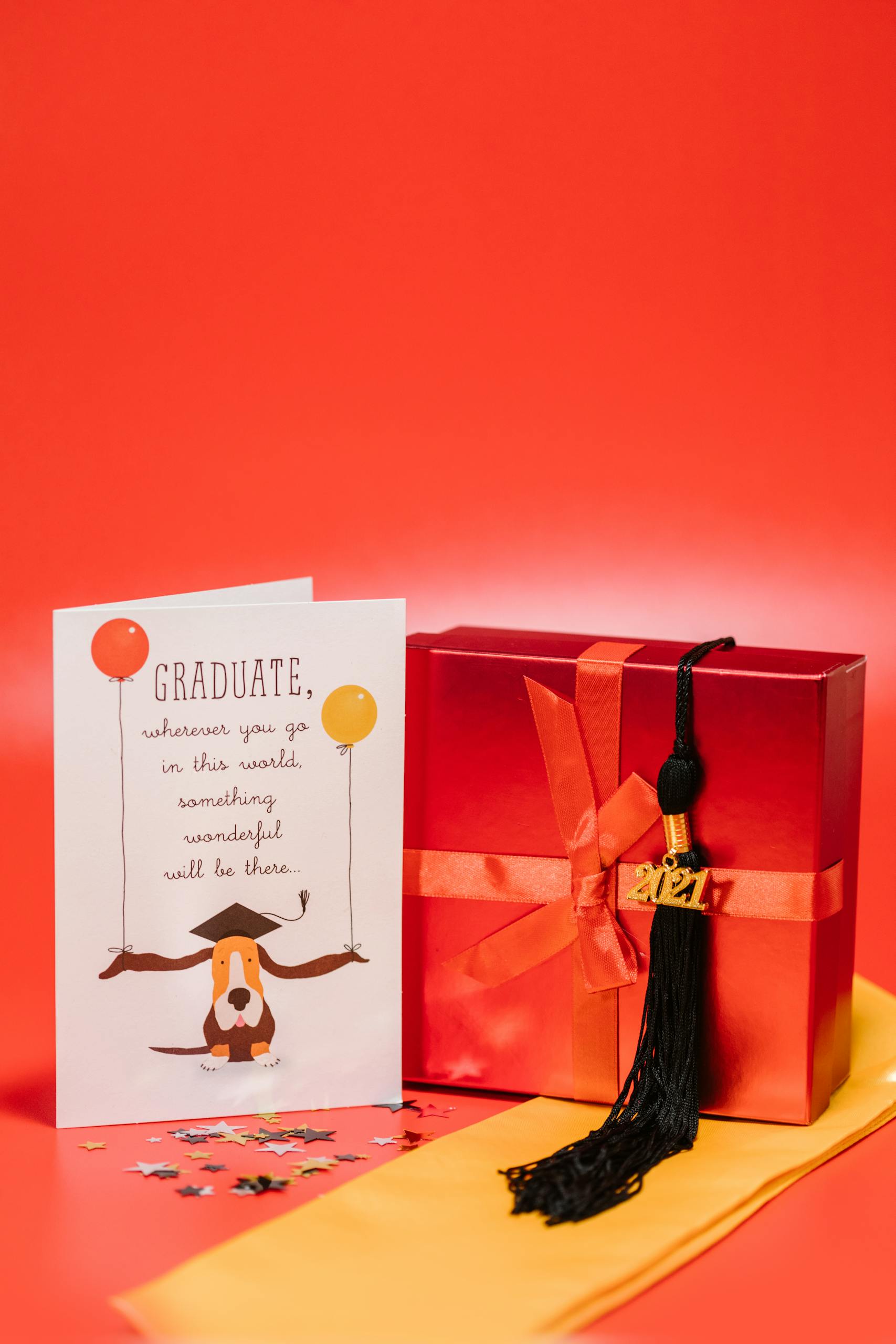 Celebrate graduation with a vibrant red gift box, card, and class of 2021 tassel. Ideal for congratulating new grads.